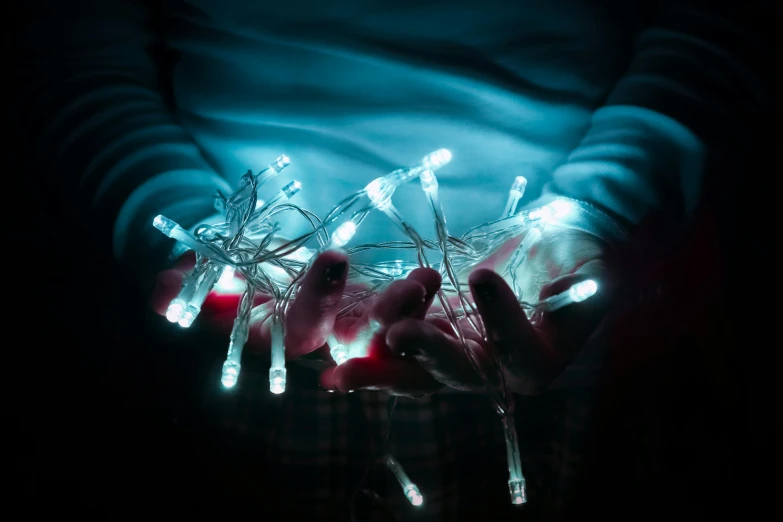 a person holding a string of lights in their hands, a hologram, inspired by Elsa Bleda, unsplash, interactive art, white and pale blue toned, horror, christmas lights, ilustration