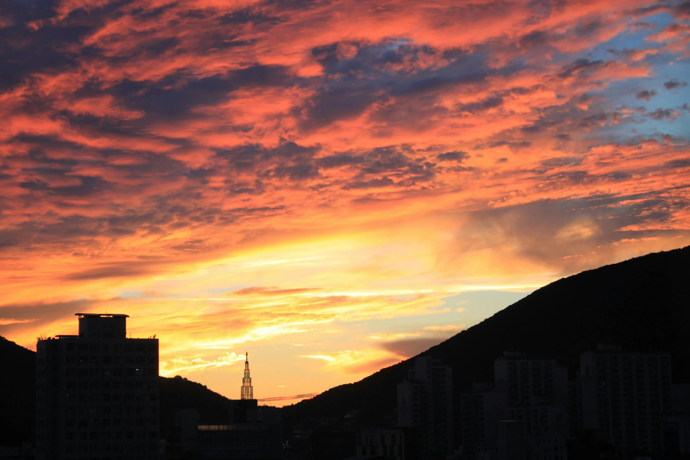 a sunset over a city with mountains in the background, by Charlotte Harding, pexels contest winner, a still of kowloon, vibrant sunset dramatic sky, photo on iphone, a colorful