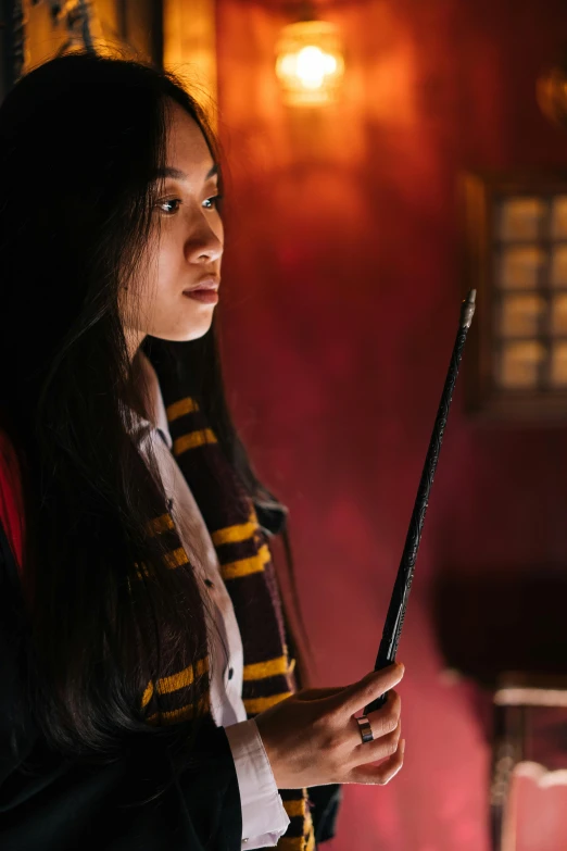 a woman in a harry potter costume holding a wand, hurufiyya, cinematic soft lighting, shot with sony alpha, student, gemma chen