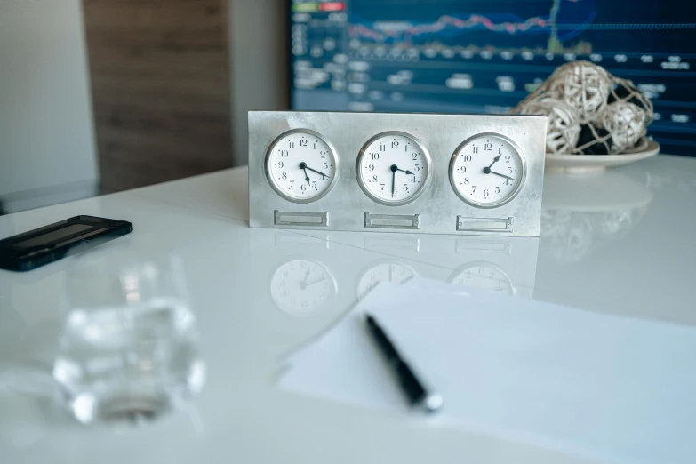 a couple of clocks sitting on top of a table, in office, profile image, white and silver, rule of three