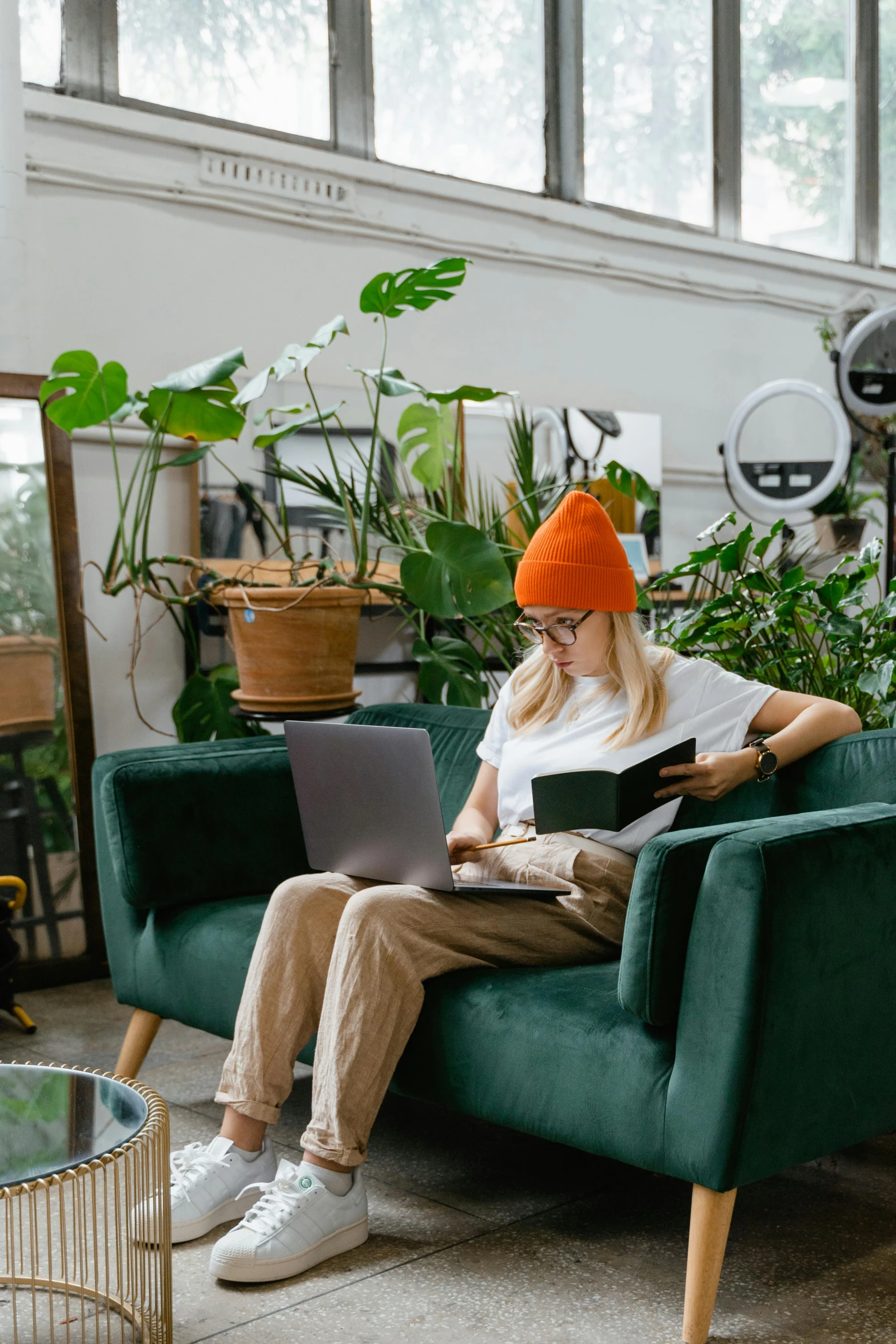 a woman sitting in a chair with a laptop, trending on pexels, maximalism, green hat, green house, green corduroy pants, plants in glasses