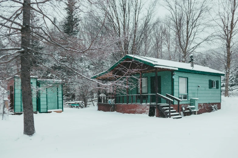a green cabin sitting in the middle of a snow covered forest, trailer park, teal aesthetic, exterior photo, several cottages