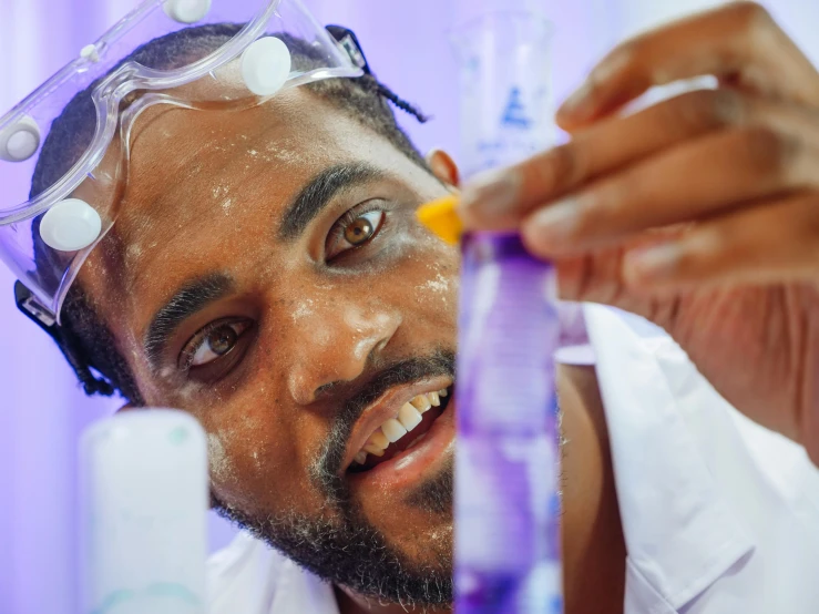 a man in a lab coat holding a tube filled with liquid, inspired by Dr. Atl, pexels contest winner, african facial features, young man in a purple hoodie, thumbnail, making of