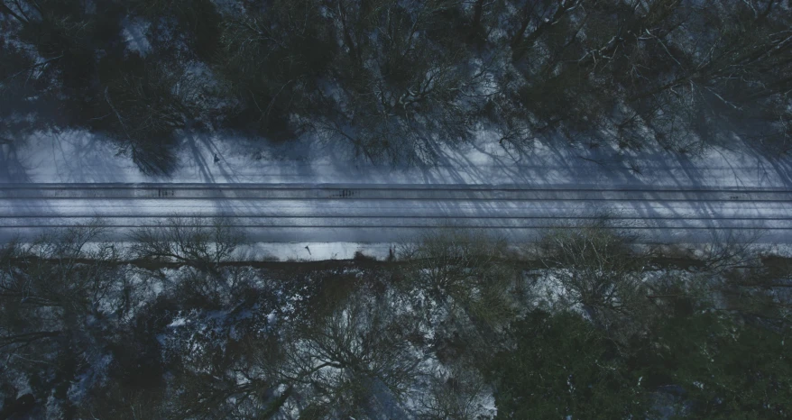 a car driving down a snow covered road, an album cover, by Adam Marczyński, pexels contest winner, realism, overhead wires, looking down at the forest floor, trains, dark lines