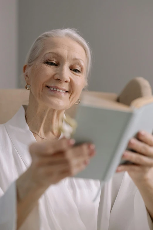 a woman sitting in a chair reading a book, gray haired, with accurate features, healthcare, gif