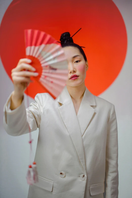 a woman in a white suit holding a red fan, an album cover, inspired by Itō Shinsui, pexels contest winner, non binary model, bao pnan, a portrait of issey miyake, ethnicity : japanese