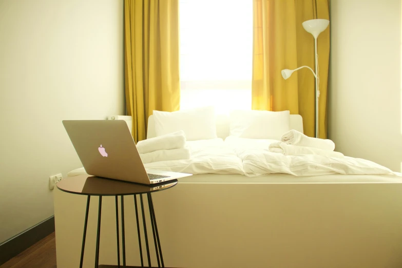a laptop computer sitting on top of a white bed, inspired by Elsa Bleda, yellow walls, white background”, airbnb, with apple