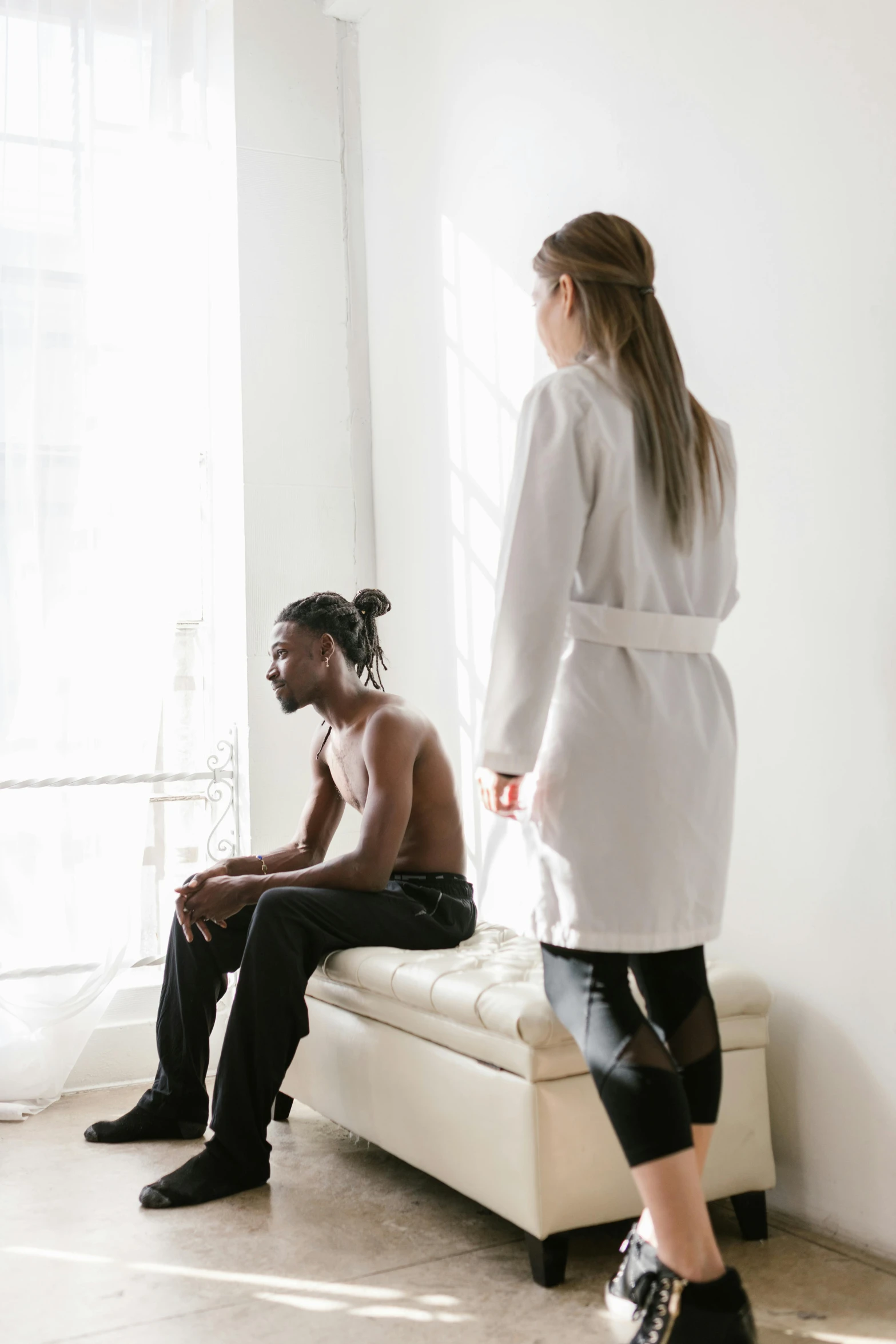 a man and a woman sitting on a bench in a room, trending on pexels, renaissance, lab coat, black human spine, man standing, non binary model