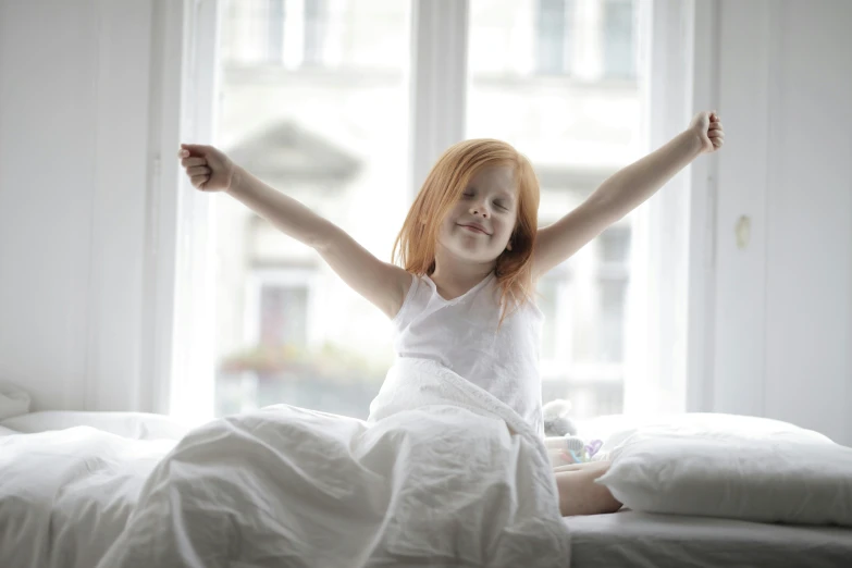 a little girl sitting on a bed with her arms in the air, pexels contest winner, happening, redhead woman, good morning, oscar winning, pristine and clean