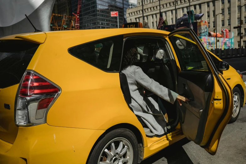 a woman sitting in the driver's seat of a yellow car, pexels contest winner, hypermodernism, in the middle of new york, a person standing in front of a, accompanying hybrid, thumbnail