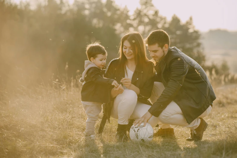 a family playing with a soccer ball in a field, pexels contest winner, elegant look, leather clothing, profile image, husband wife and son