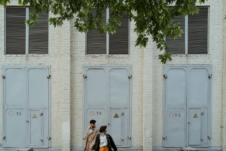 a couple of people that are walking down the street, a photo, inspired by Rachel Whiteread, pexels contest winner, bengal school of art, refrigerated storage facility, 3 doors, exterior photo