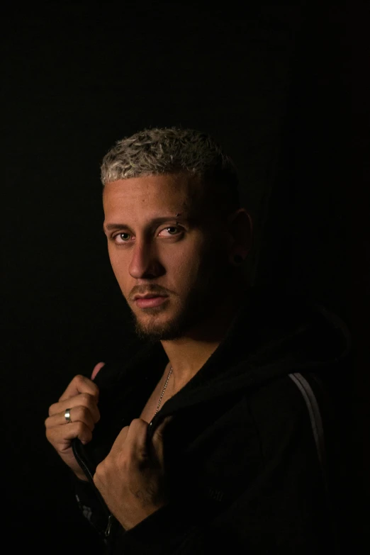 a man standing in front of a black background, an album cover, pexels contest winner, les nabis, sam nassour, neymar jr, androgynous person, gal yosef