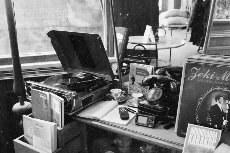 a black and white photo of a desk with a record player, a still life, inside a shed, books all over the place, vintage - w 1 0 2 4, complex and detailed