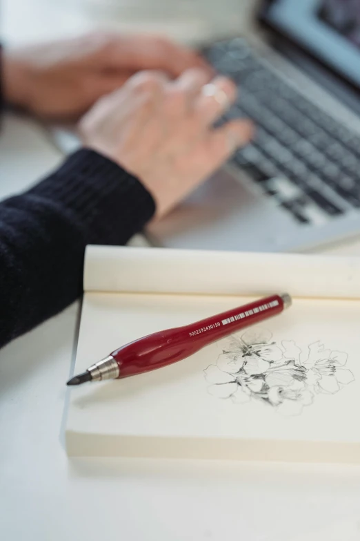 a person sitting at a desk with a laptop and a pen, visual art, silver and crimson ink, full product shot, fine point pen, maroon red