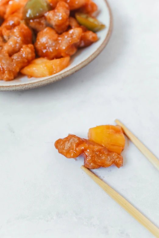 a close up of a plate of food with chopsticks, peach, battered, f / 2 0, polished