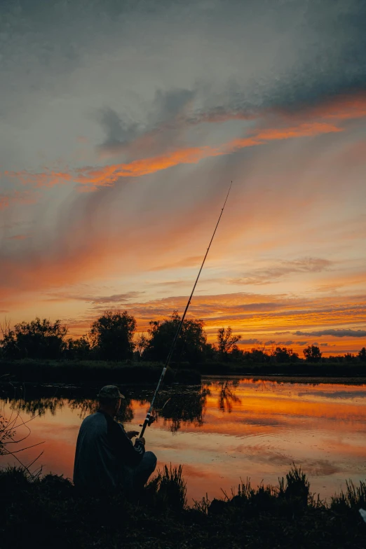 a man fishing in a lake at sunset, a picture, by Jan Tengnagel, pexels contest winner, vivid sky, on a riverbank, minn