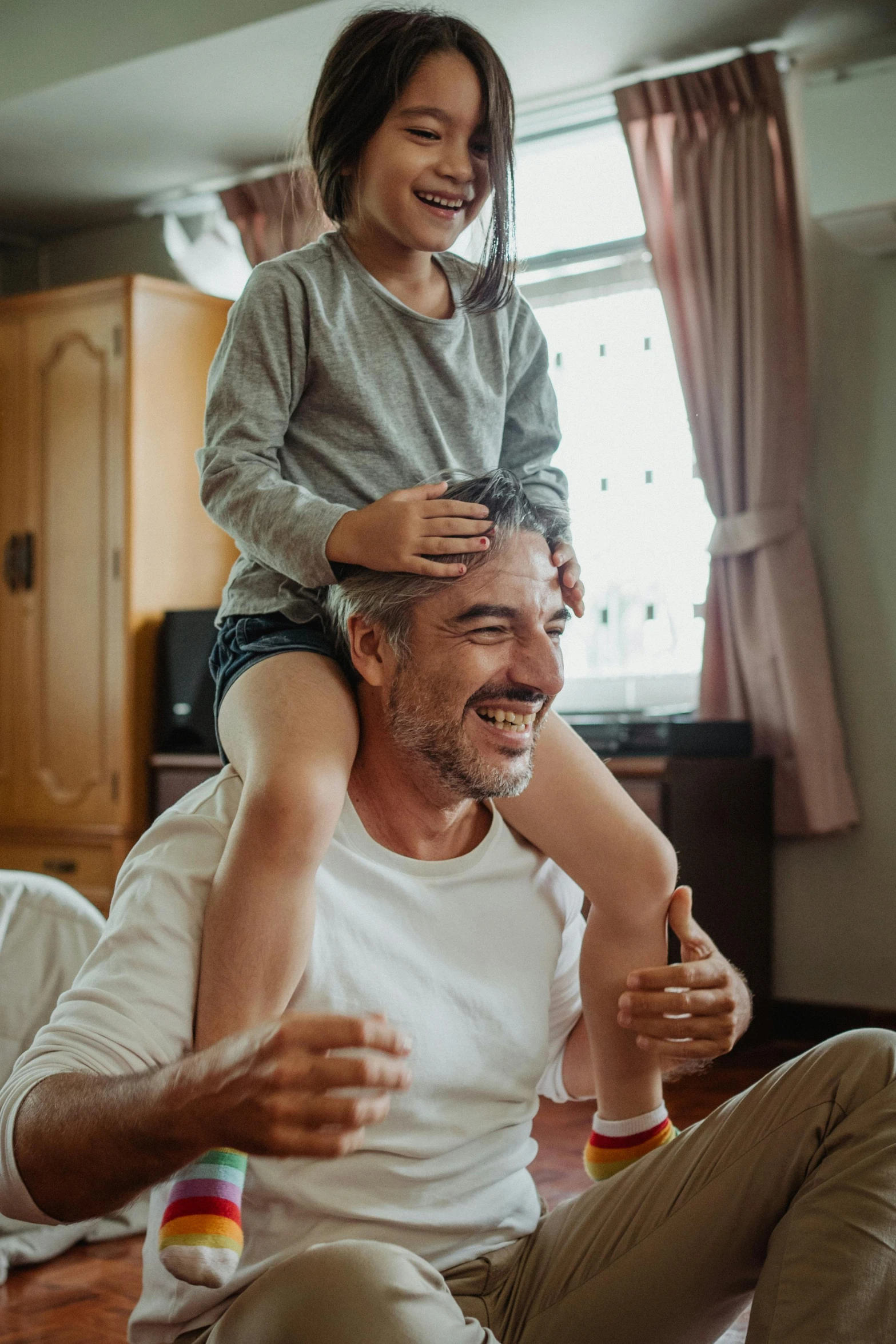 a man holding a little girl on his shoulders, pexels contest winner, two buddies sitting in a room, smiling playfully, thumbnail, 45 years old men