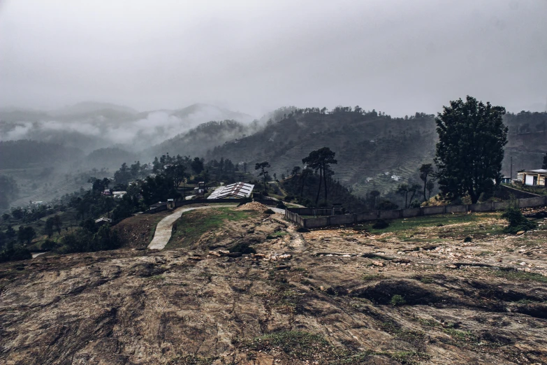 a view of a village from the top of a hill, pexels contest winner, hurufiyya, misty ominous atmosphere, sri lanka, rocky ground, under a gray foggy sky