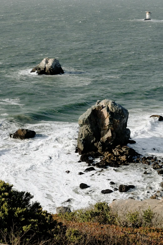 a view of a body of water with a lighthouse in the distance, rock arcs, san francisco, ((rocks)), zoomed in shots