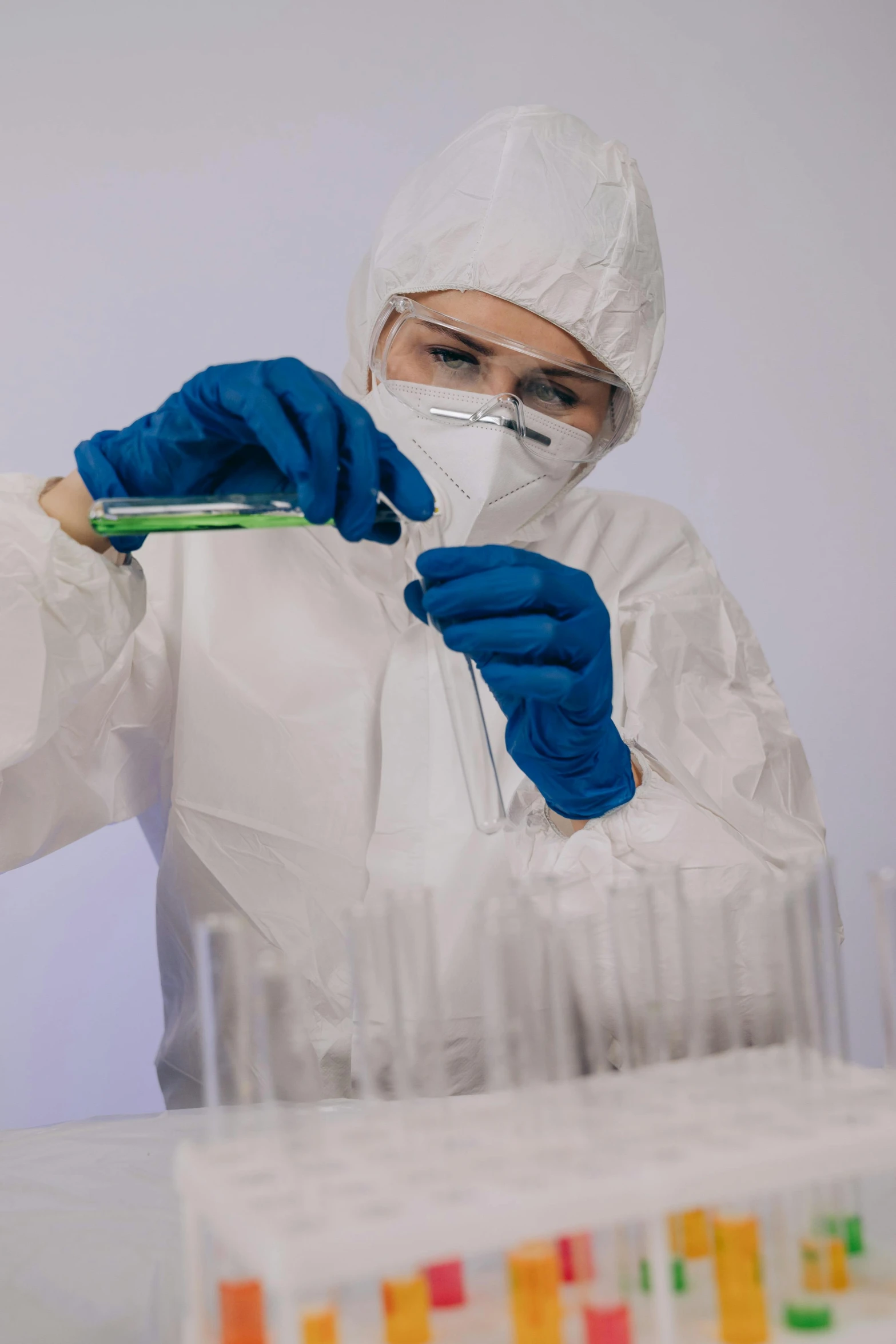 a woman in a lab coat holding a test tube, by Adam Marczyński, pexels, analytical art, staff wearing hazmat suits, digging, many cryogenic pods, panels