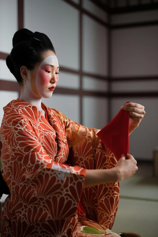 a woman in a kimono sitting on the floor, a silk screen, trending on unsplash, noh theatre mask, square, making of, ( ( theatrical ) )