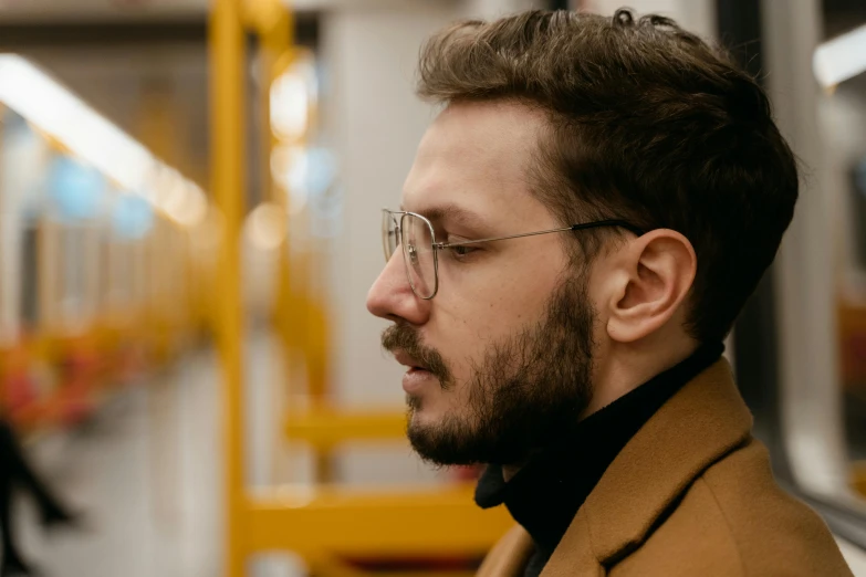 a close up of a person on a train, by Adam Marczyński, trending on pexels, hyperrealism, with glasses and goatee, elegant profile pose, blond brown stubble thin beard, wearing a turtleneck and jacket