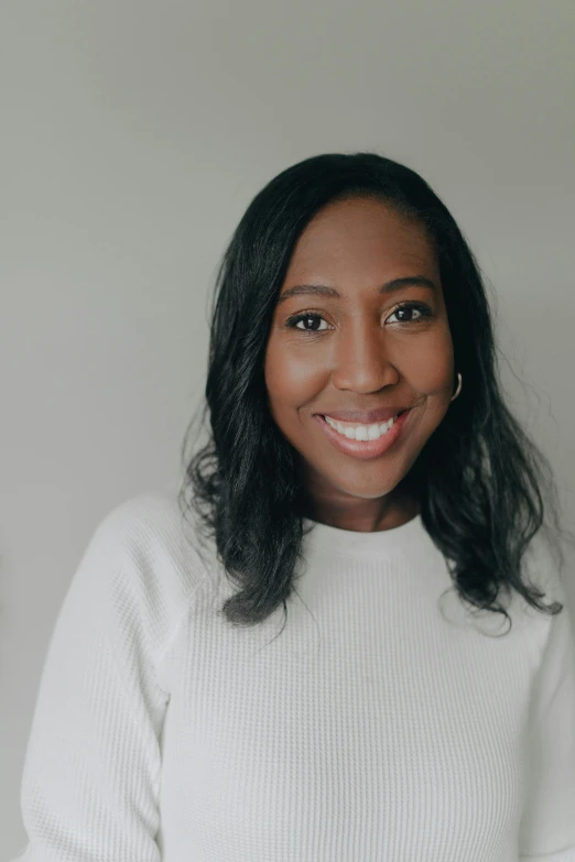 a woman in a white sweater smiles at the camera, by Dulah Marie Evans, smiling into the camera, vp of marketing, wide establishing shot, dark skinned