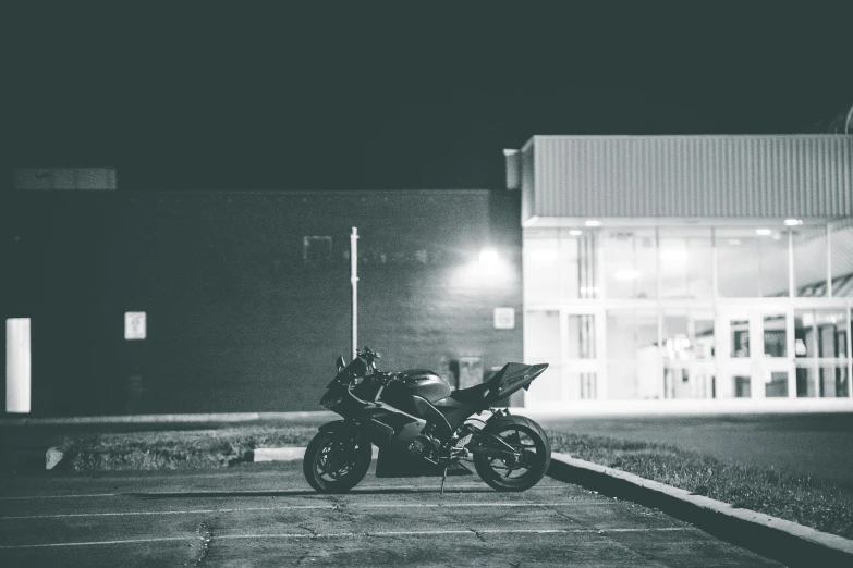 a black and white photo of a motorcycle parked in a parking lot, by Daniel Seghers, pexels contest winner, night outside, stealth, bulky build, sitting on the ground