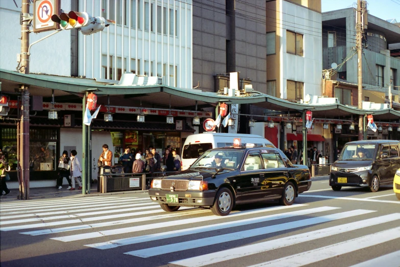 a group of cars driving down a street next to tall buildings, shin hanga, toyota cresta, near a japanese shrine, taxi, 🚿🗝📝