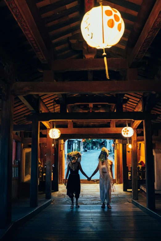 a couple of women standing next to each other holding hands, unsplash, feudal japanese setting, long hall way, bride, vietnam