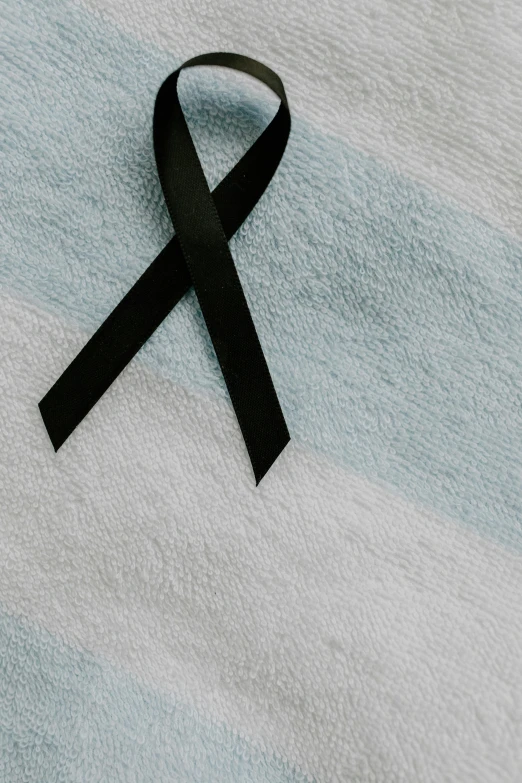 a black ribbon laying on top of a towel, pale blue skin, multiple stories, healthcare, aesthetics