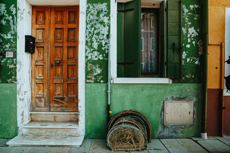 a motorcycle parked in front of a green building, a photo, inspired by Marià Fortuny, pexels contest winner, arte povera, doors to various living quarters, venice biennale's golden lion, vines and cracked wood, background image