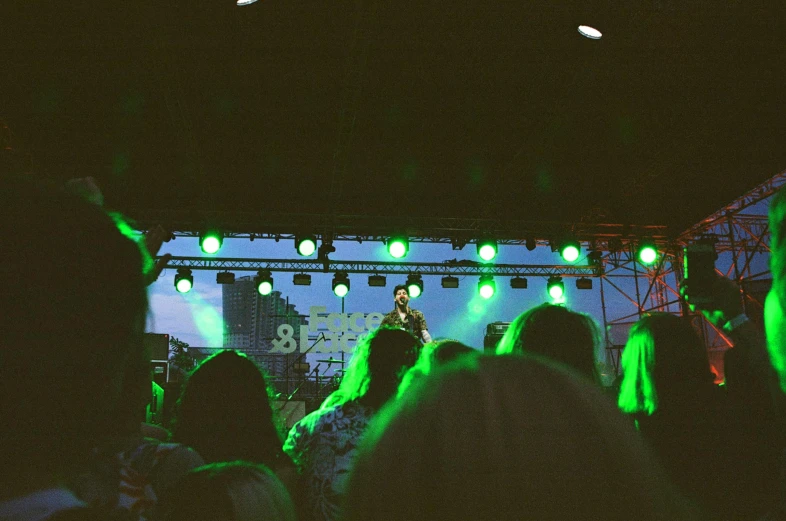 a group of people standing on top of a stage, an album cover, unsplash, green lights, summer festival night, 33mm photo, mr beast