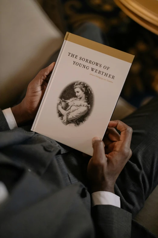 a man in a suit is reading a book, an album cover, by Joseph Severn, young noble, still from film, photographed for reuters, the warm