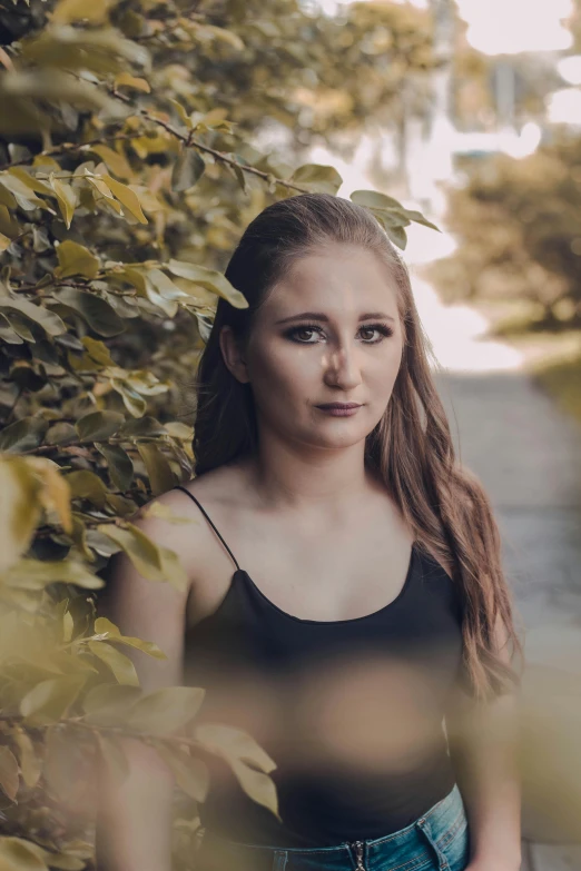 a beautiful young woman standing in front of a bush, inspired by Elsa Bleda, pexels contest winner, serious focussed look, low quality photo, music video, brown haired