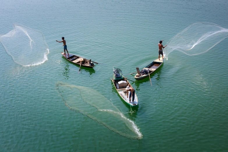 a couple of boats that are in the water, by Yasushi Sugiyama, pexels contest winner, hurufiyya, people at work, schools of fish, lagoon, nivanh chanthara