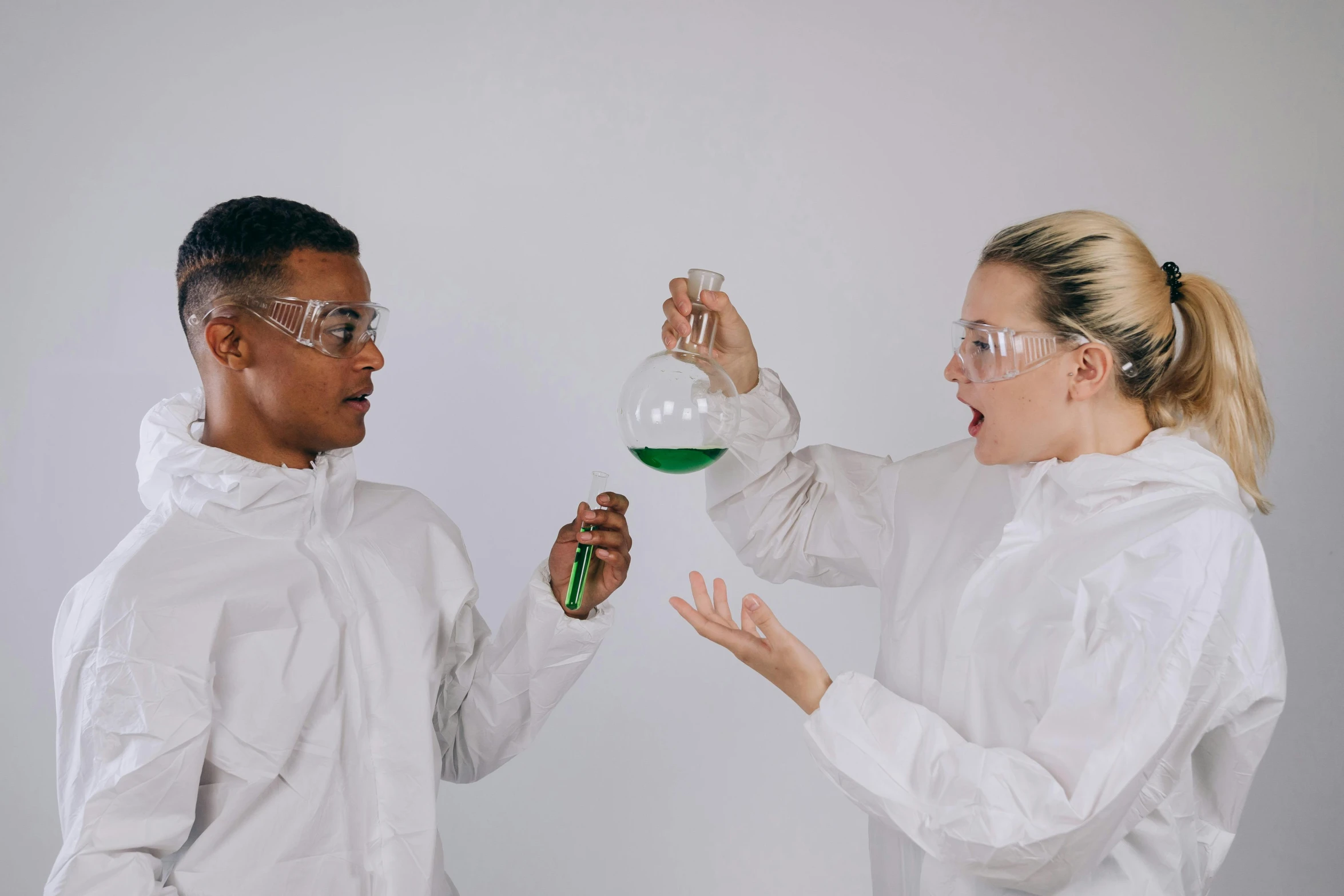 a man and a woman in white lab coats holding flasks, trending on pexels, analytical art, green robes, balancing the equation, gif, curious