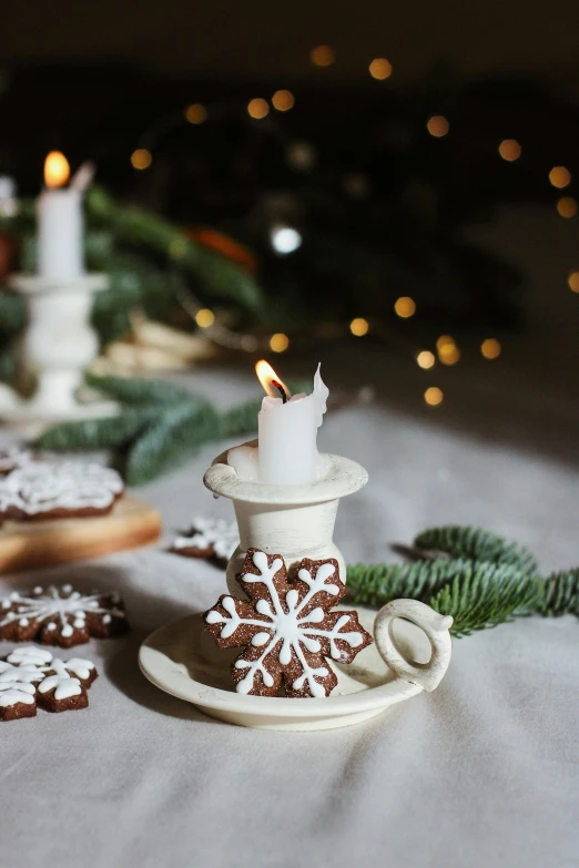 a table topped with cookies and a lit candle, by Julia Pishtar, shutterstock contest winner, folk art, white ceramic shapes, snowflakes, shot with sony alpha 1 camera, made of glazed