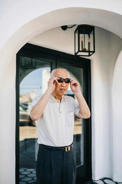 an older man looking through a pair of sunglasses, inspired by Li Tiefu, unsplash, renaissance, standing outside a house, conde nast traveler photo, wearing polo shirt, about to enter doorframe