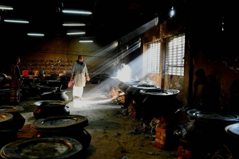 a man standing in a room filled with pots and pans, a picture, pexels contest winner, smoke coming from tires, in warehouse, photograph credit: ap, shining lights