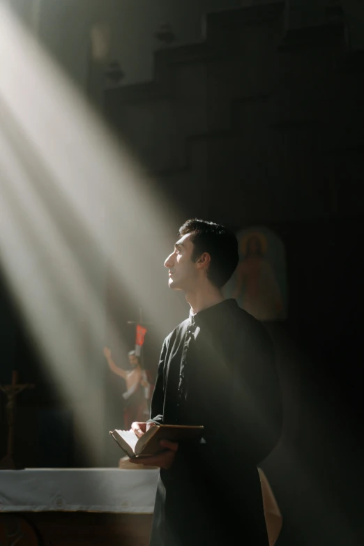 a man that is standing in front of a table, pexels contest winner, light and space, scene from church, ( ( theatrical ) ), light ray, catholic