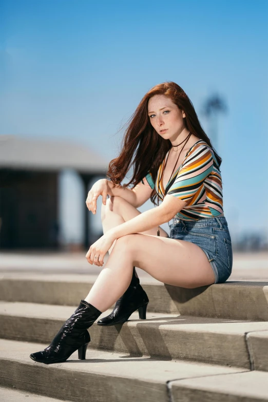 a woman sitting on the steps of a building, she has long orange brown hair, non binary model, portrait of maci holloway, sitting on top a table