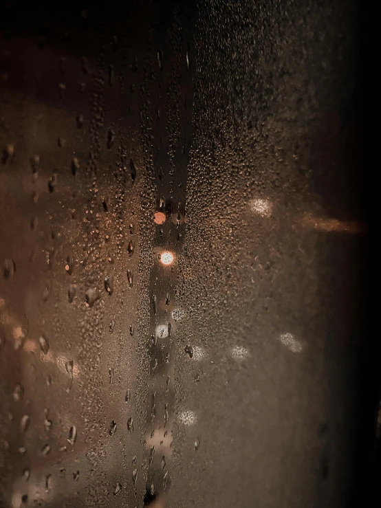 a close up of a window with raindrops on it, inspired by Elsa Bleda, pexels contest winner, australian tonalism, todd hido, ☁🌪🌙👩🏾, nighttime, ambient amber light