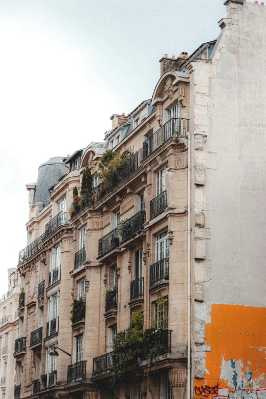 a building with graffiti on the side of it, a photo, trending on unsplash, paris school, multiple stories, orange roof, quaint, crenellated balconies