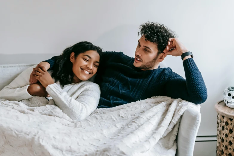 a man and a woman laying on a couch, trending on pexels, cozy bed, profile image, smiling, looking to the right