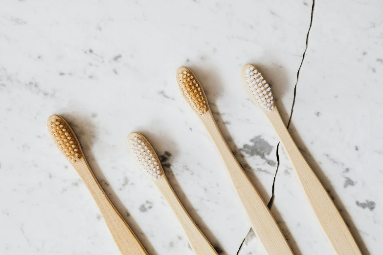 four bamboo toothbrushes lined up on a marble surface, by Nicolette Macnamara, trending on pexels, helga pataki's teeth, eco, spoon, 1 2 9 7