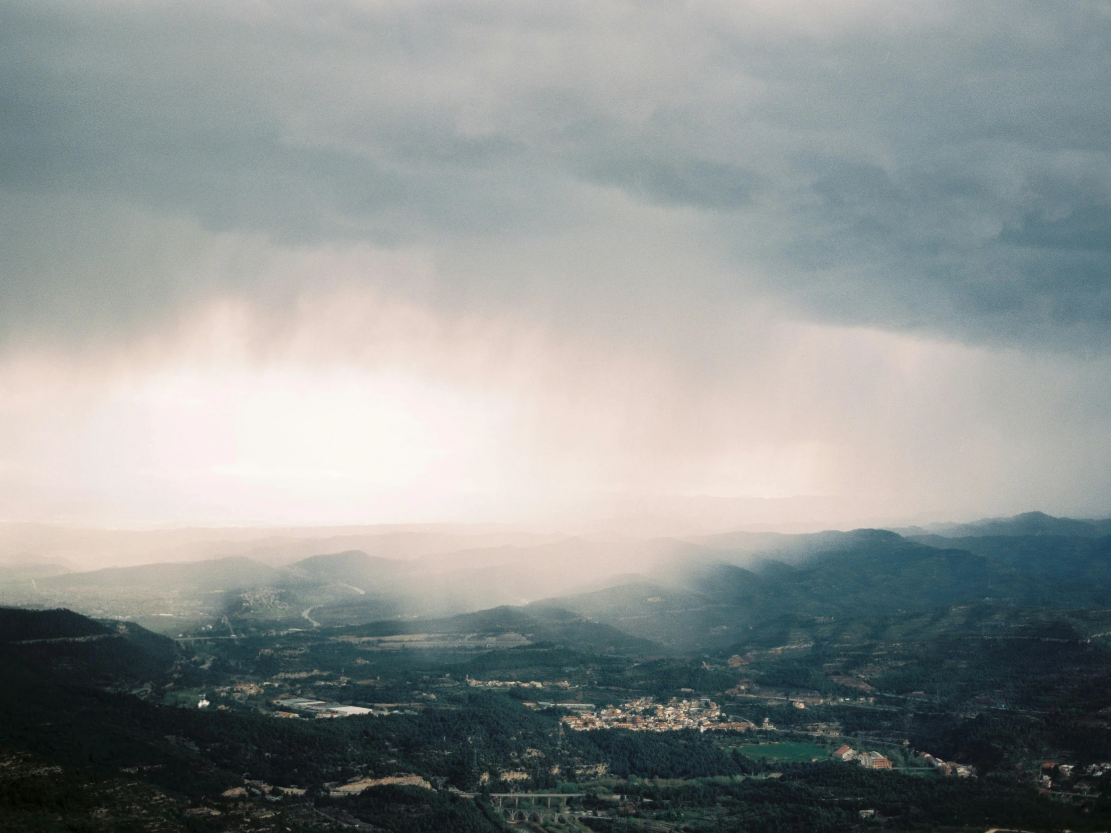 a person riding a snowboard on top of a snow covered slope, a picture, unsplash contest winner, happening, distant rainstorm, distant town in valley and hills, thunderstorms, marbella landscape