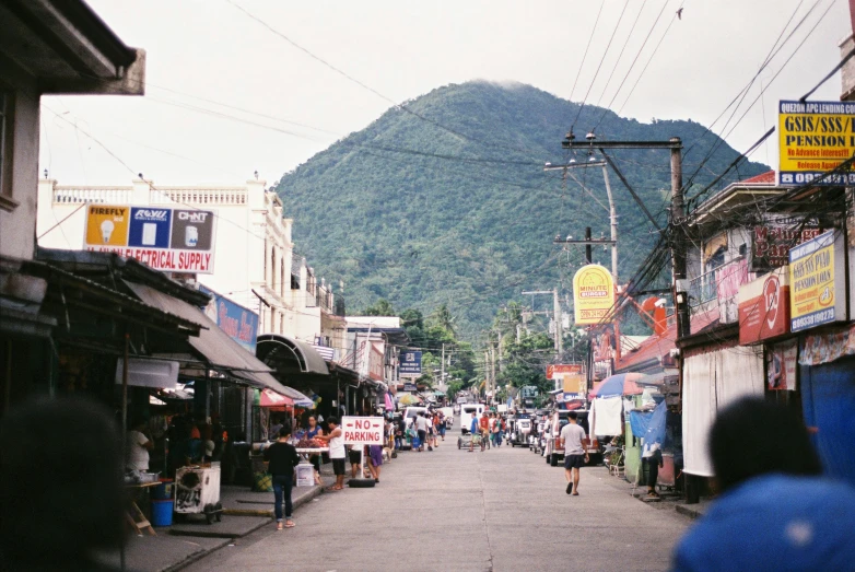 a city street with a mountain in the background, market stalls, shot onfilm, tropical coastal city, grey