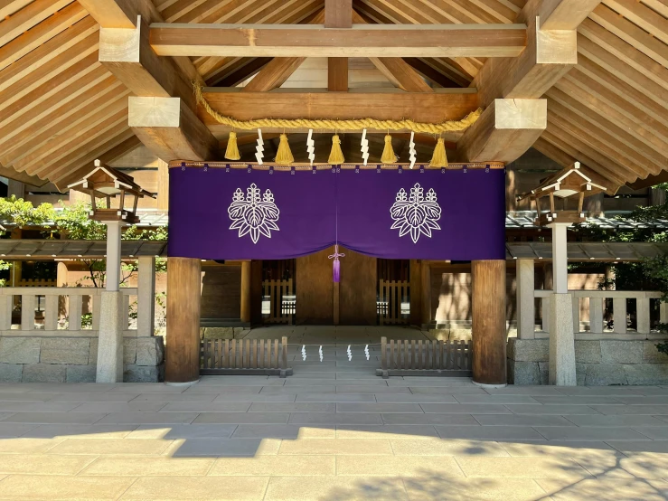 a large purple banner hanging from the side of a building, inspired by Itō Jakuchū, unsplash, sōsaku hanga, in an ancient altar, clean and pristine design, covered outdoor stage, symmetrical crown